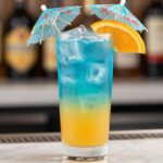 drink z blue curacao i sokiem pomarańczowym w wysokiej szklance z lodem